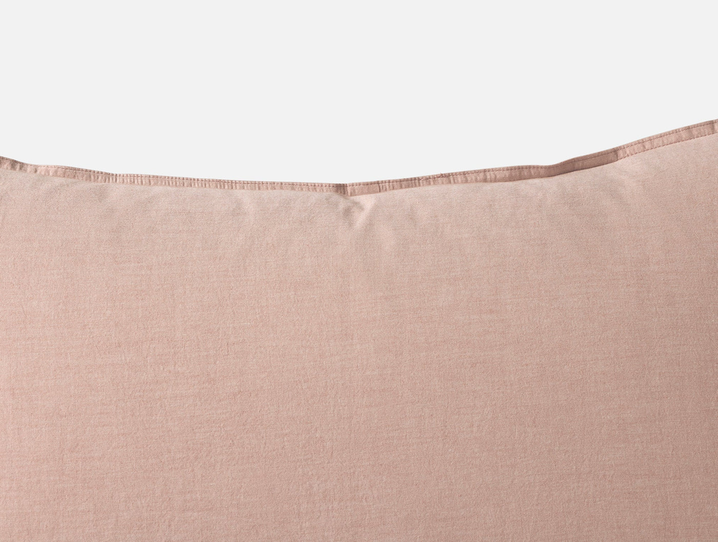 Close-up of blush Coyuchi Crinkled Percale sham top edge with visible hem stitching.
