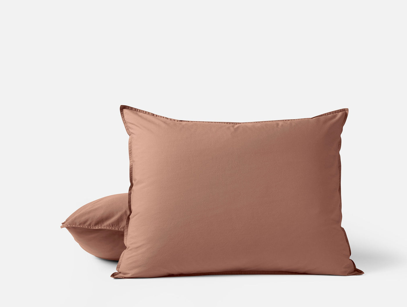 Two terracotta Coyuchi Crinkled Percale pillow shams stacked against a white background.