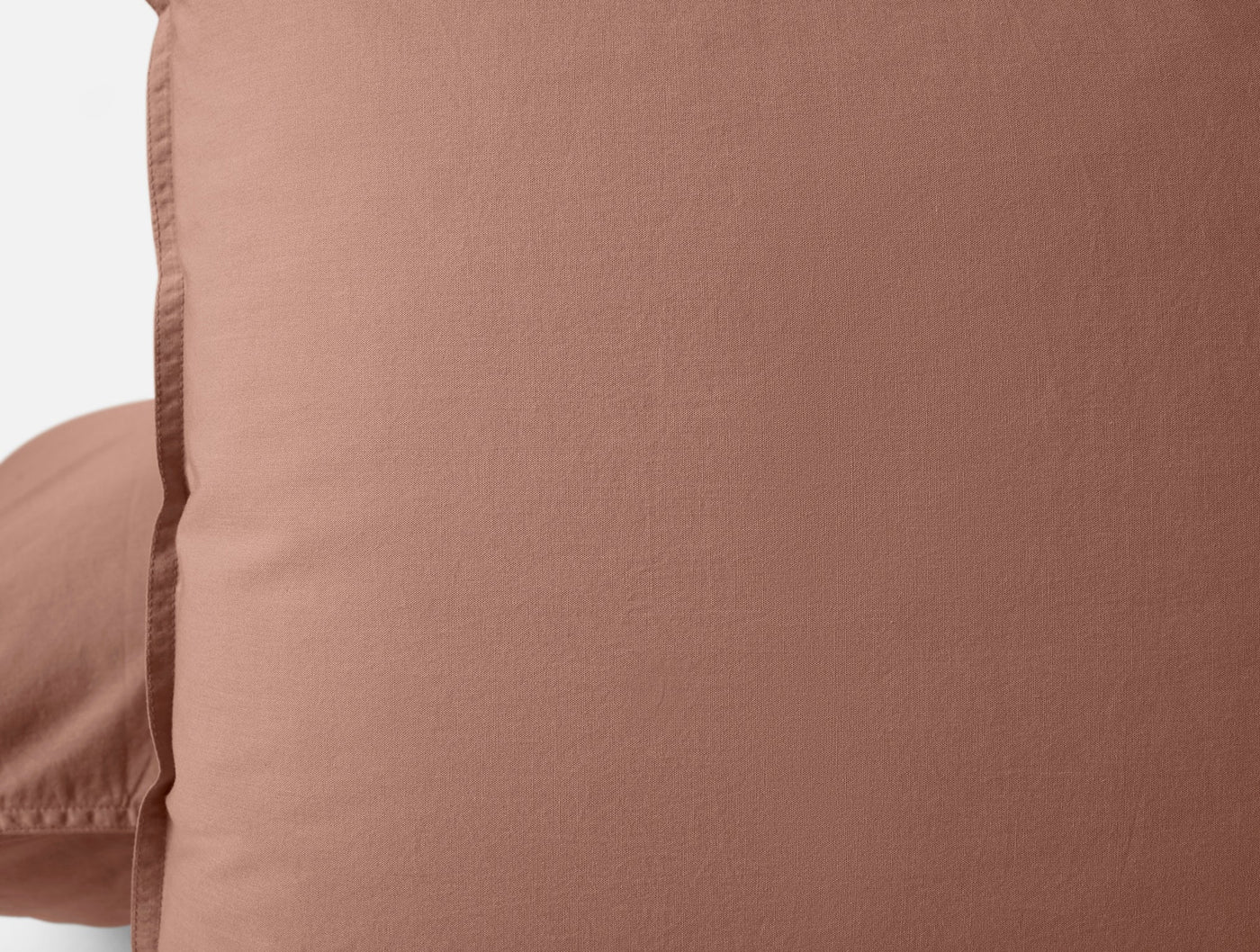 Close-up of Coyuchi Crinkled Percale pillow sham in terracotta showing textured weave.