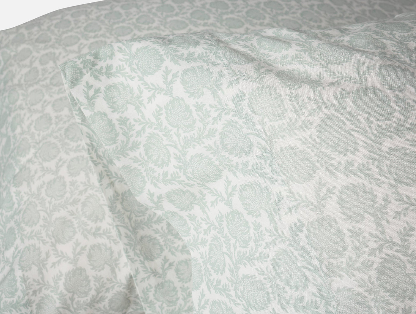 Close-up of sage floral print on white percale fabric, softly draped.