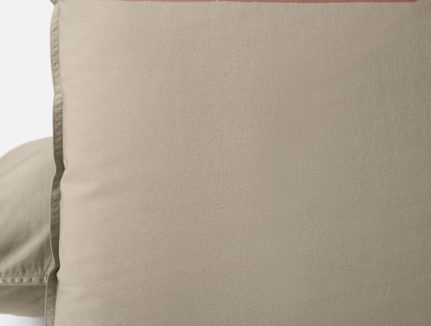 Close-up of Coyuchi Crinkled Percale pillowcase in sand with coral hem detail.