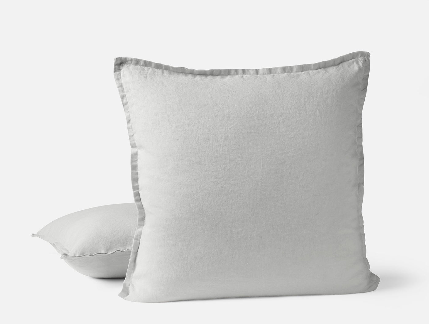 Two white Coyuchi Relaxed Linen pillow covers, front pillow showing gray flange trim detail.