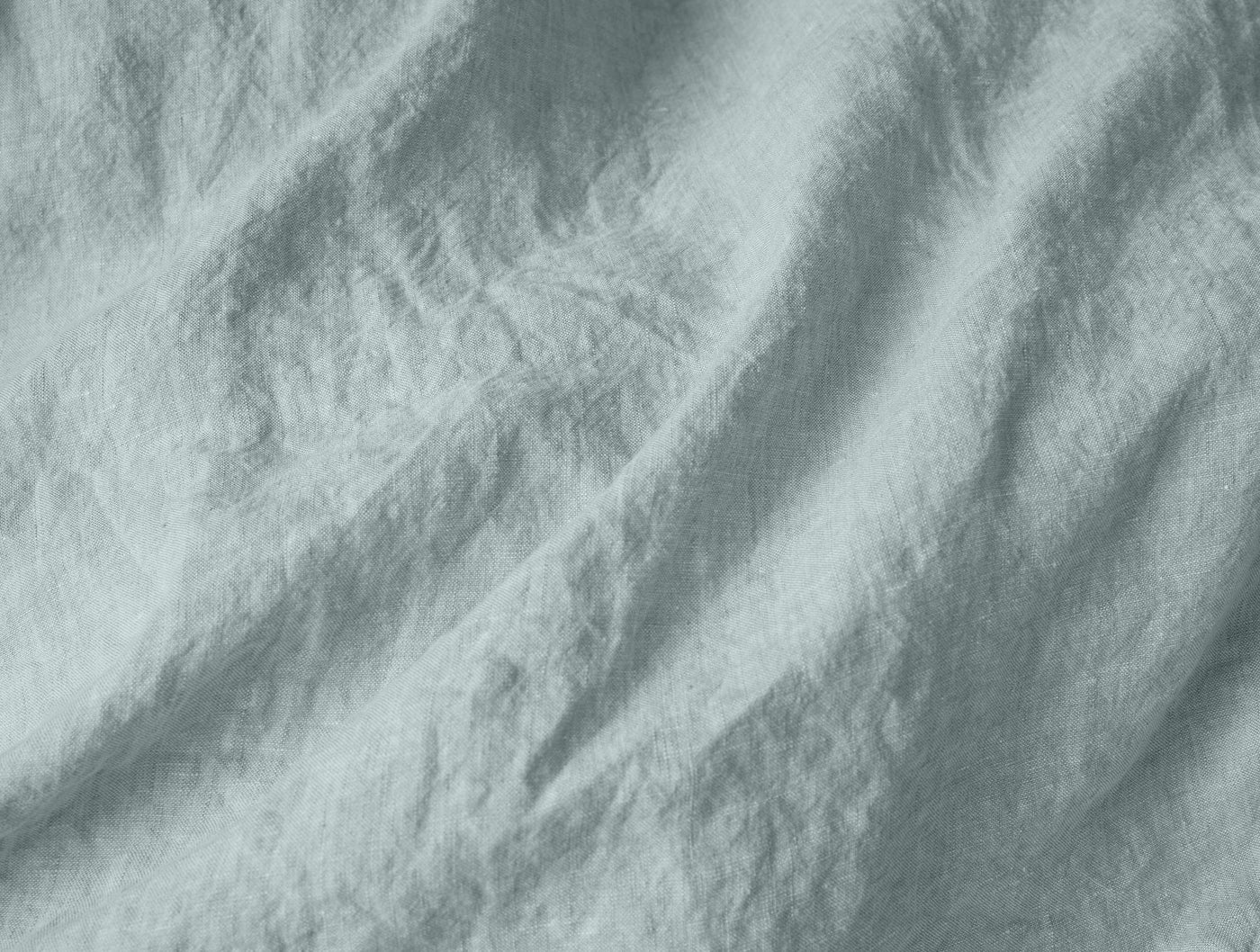 Close-up of Coyuchi Relaxed Linen duvet cover in mist, showing softly rumpled washed linen texture.