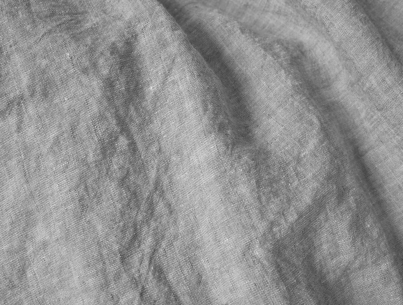 Close-up of draped pewter linen fabric showing natural woven texture and soft folds.