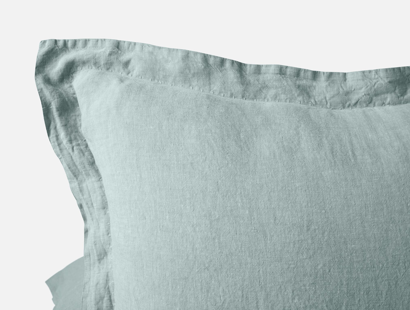 Close-up of Coyuchi Relaxed Linen sham corner in sage, showing flange edge and natural linen texture.