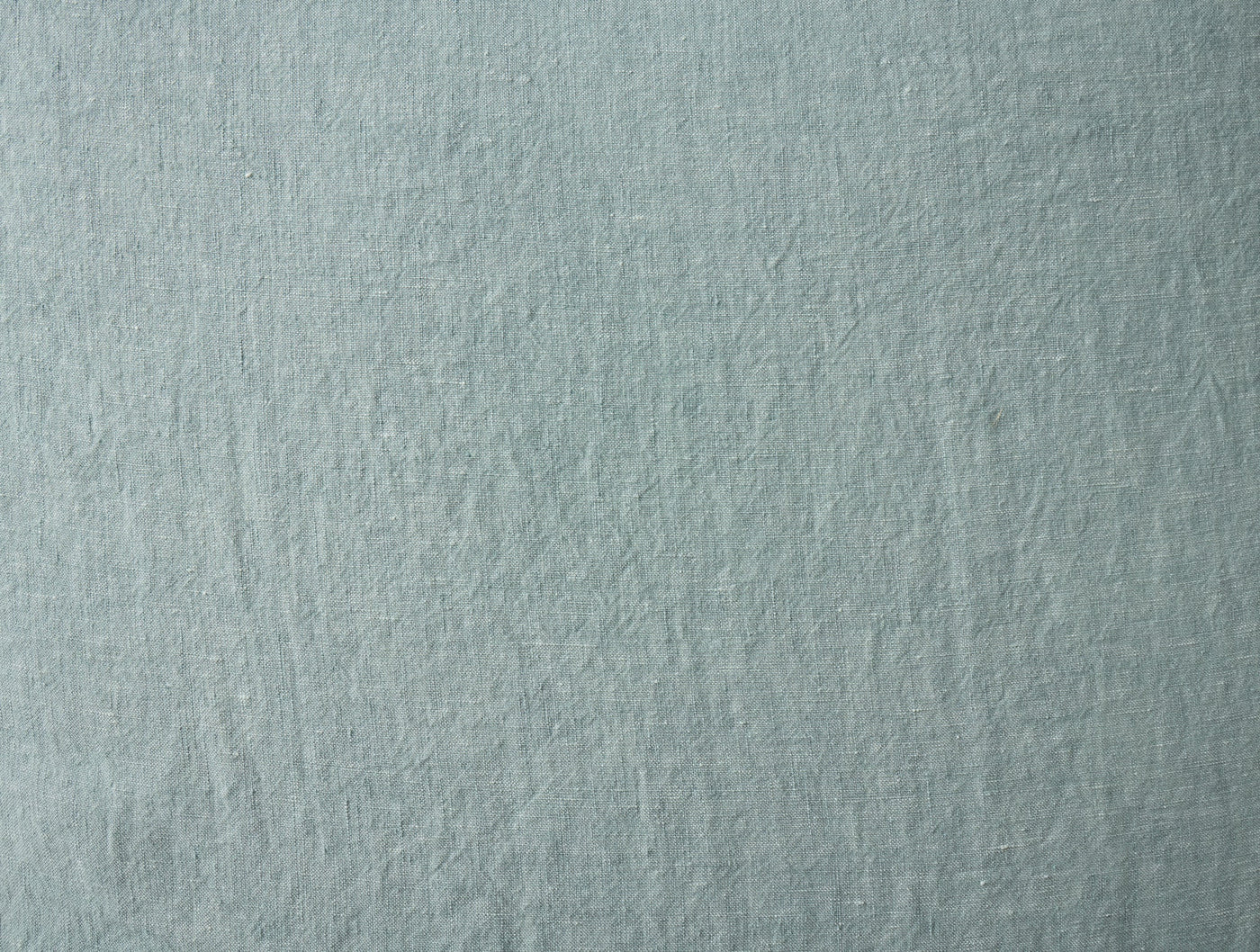Close-up of Coyuchi Relaxed Linen sheet in soft sage, showing natural woven texture.