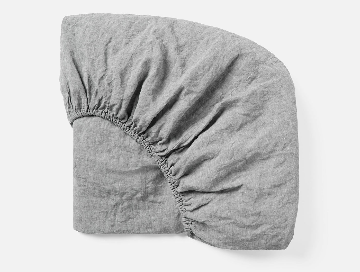 Corner detail of Coyuchi Relaxed Linen fitted sheet in grey showing elastic and drape.