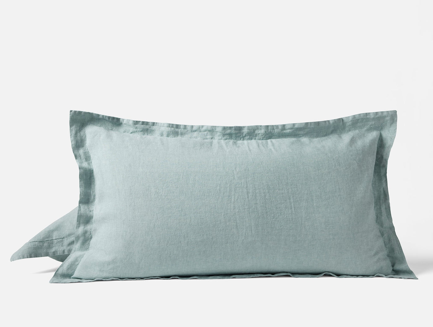 Sage green linen pillow sham with relaxed texture and wide flat border, angled view.