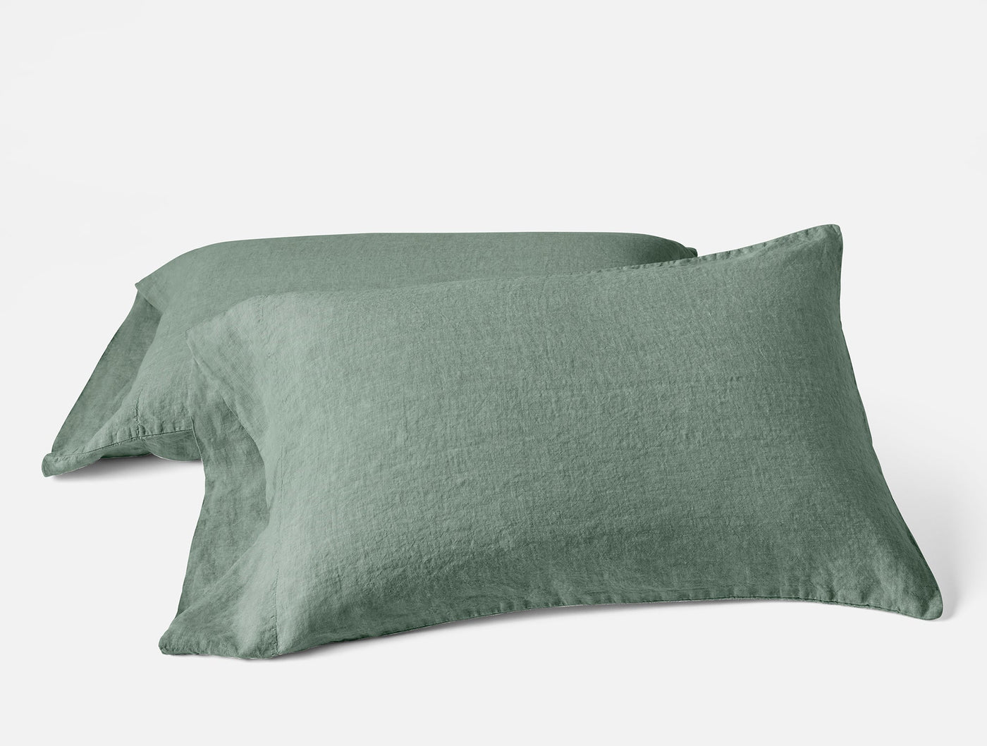 Close-up of two sage Coyuchi Relaxed Linen pillowcases stacked, showing natural texture.