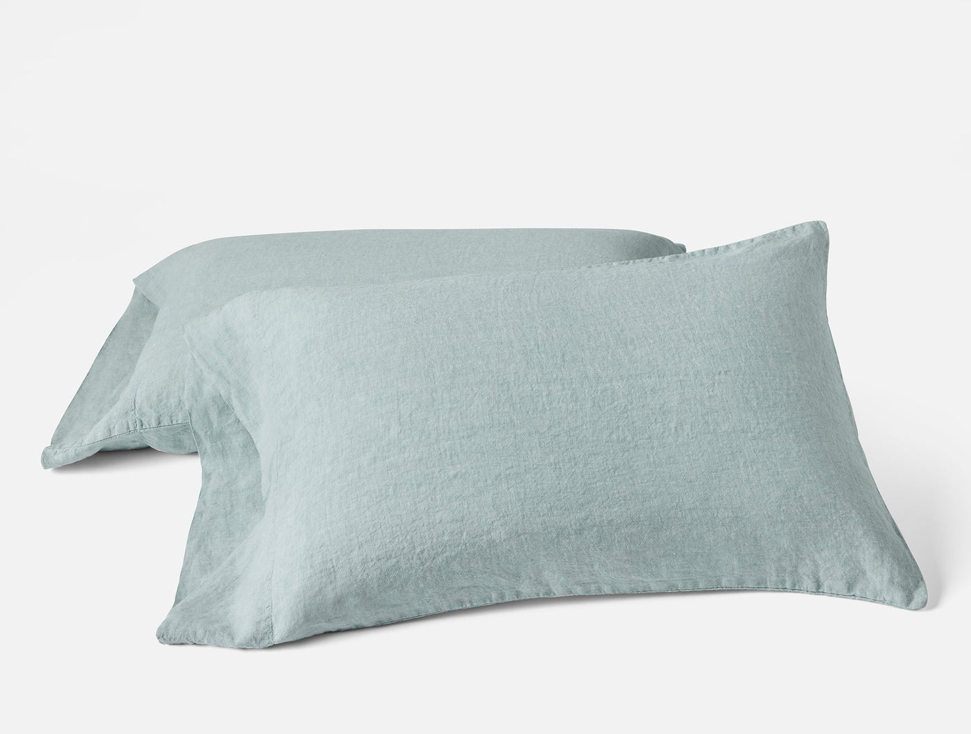 Two Coyuchi Relaxed Linen pillowcases in mist blue, stacked at an angle on white background.