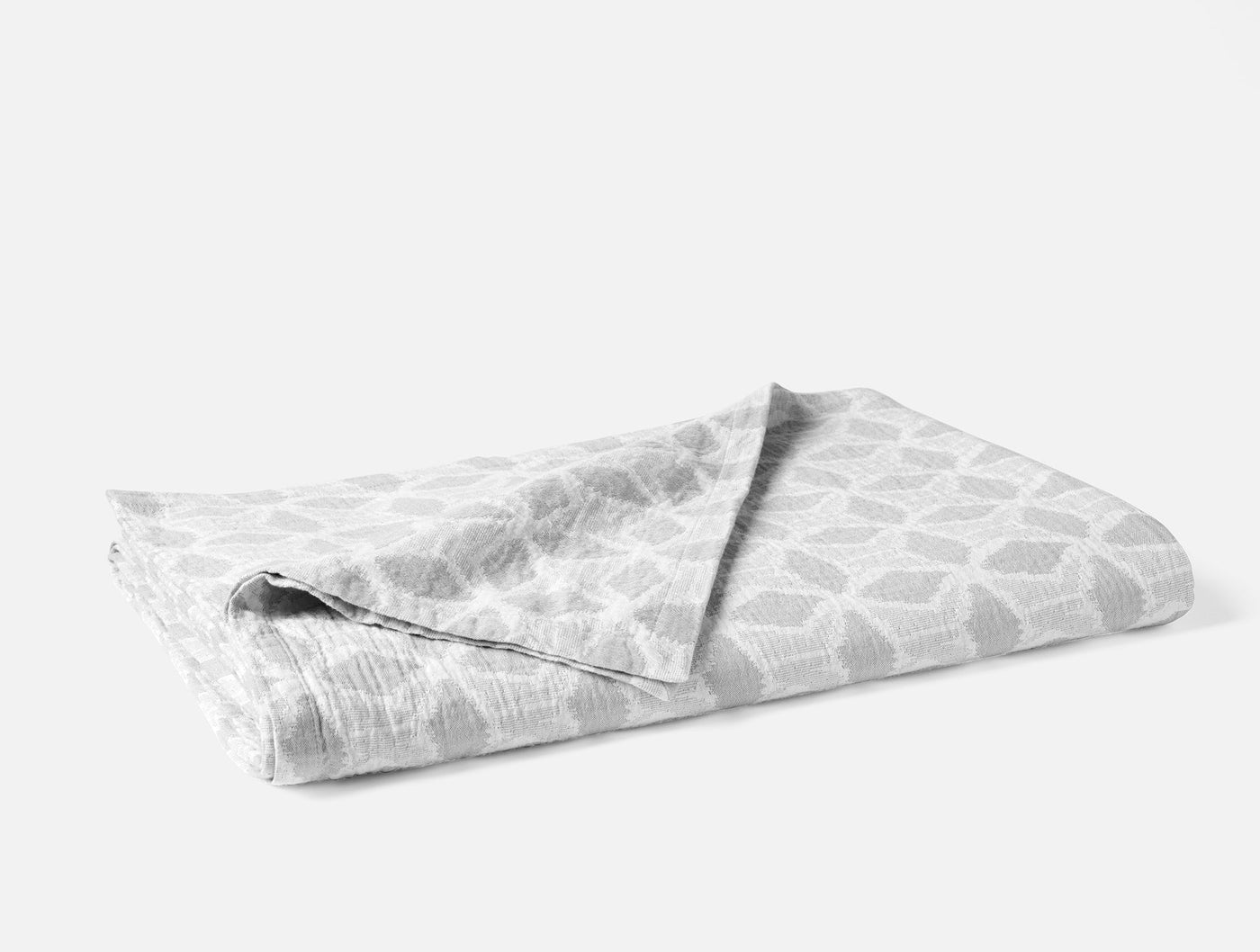 Folded Coyuchi Palomar blanket showing silver geometric honeycomb pattern on white ground.