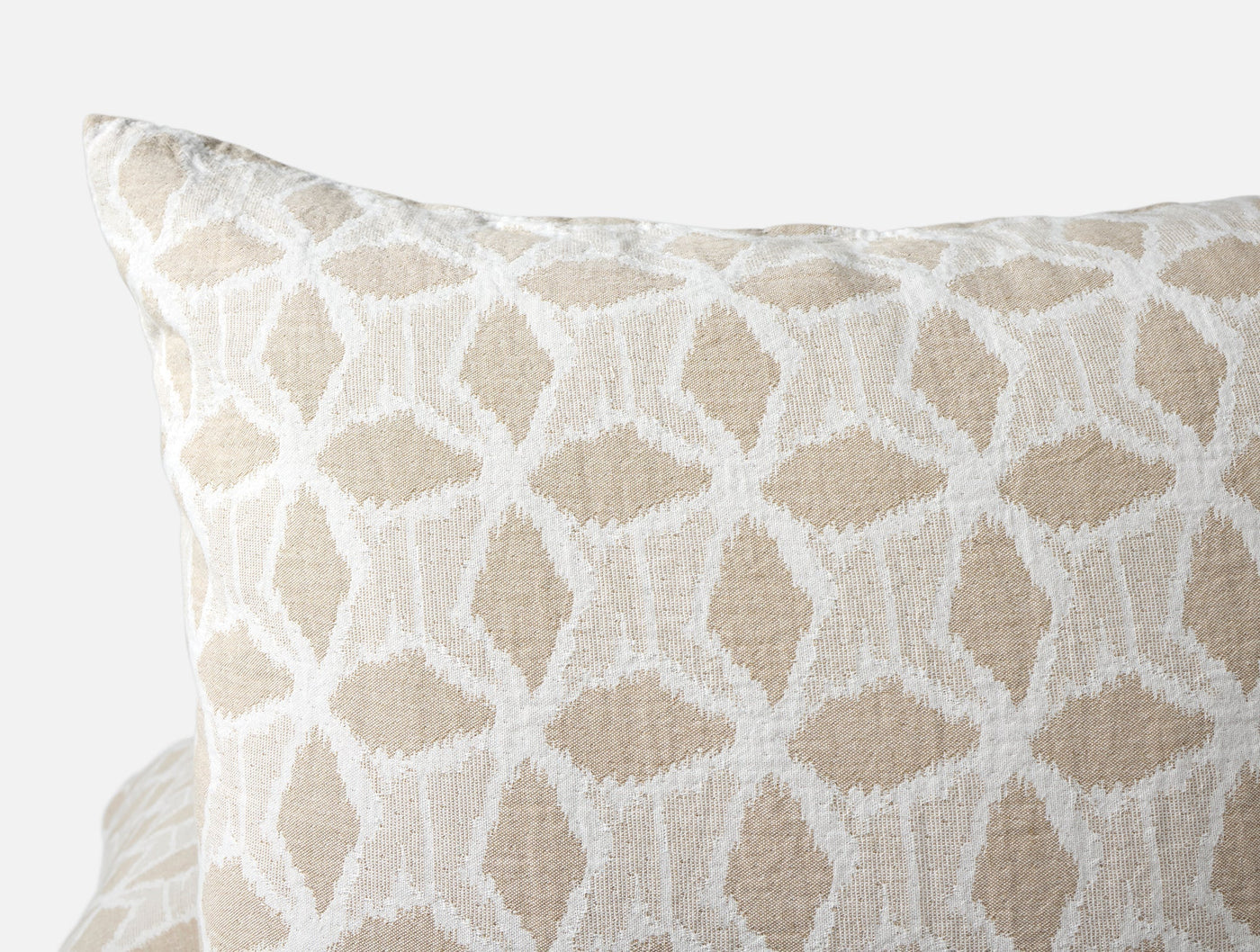 Close-up of Coyuchi Palomar sham in natural linen with white geometric ikat pattern.