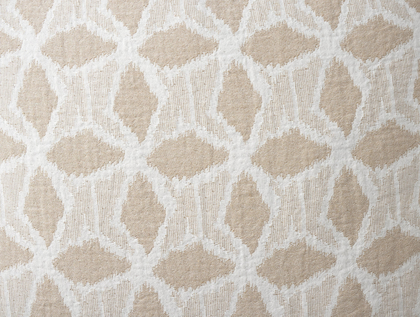 Close-up of Coyuchi Palomar sham's woven geometric diamond pattern in ivory on sand.