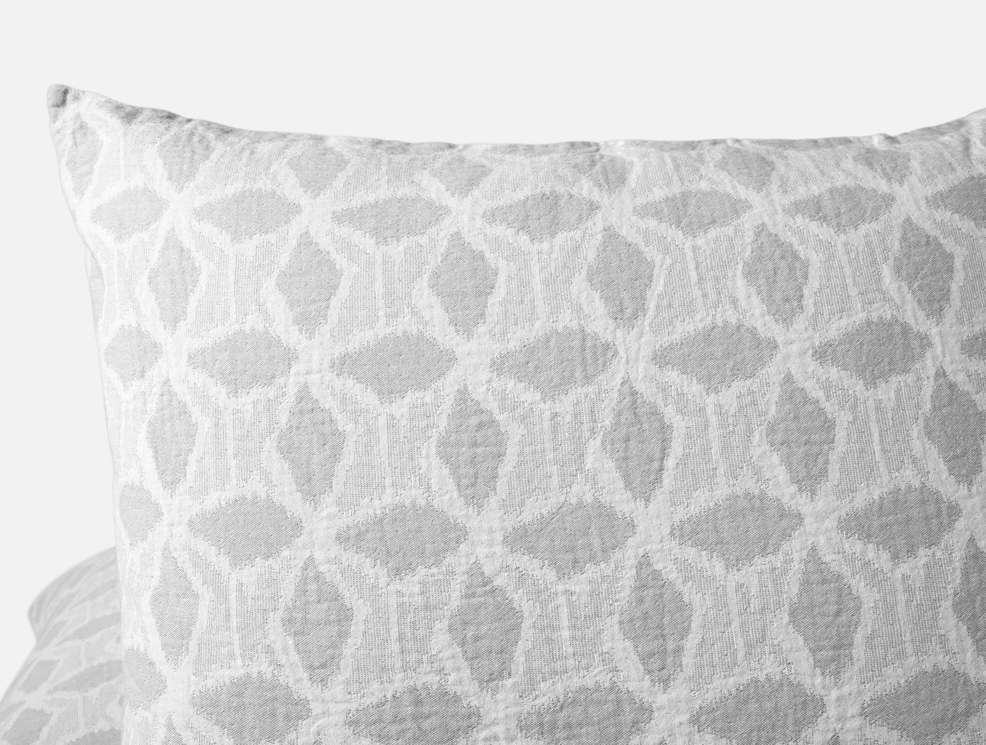 Close-up of Coyuchi Palomar sham showing grey geometric ikat pattern on textured cotton.