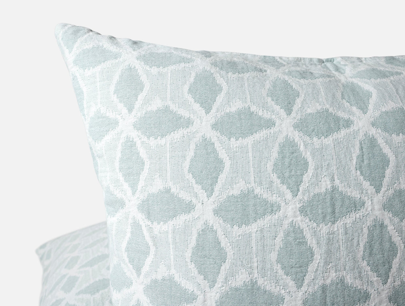 Close-up of Coyuchi Palomar sham corner, seafoam geometric ikat pattern with textured weave.