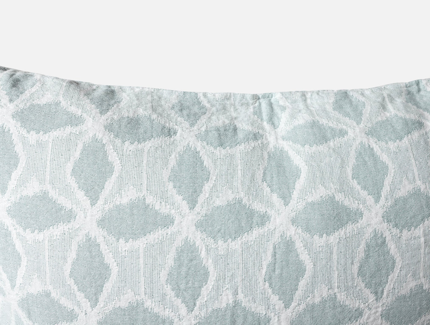 Close-up of Coyuchi Palomar sham showing woven geometric lattice pattern in seafoam.