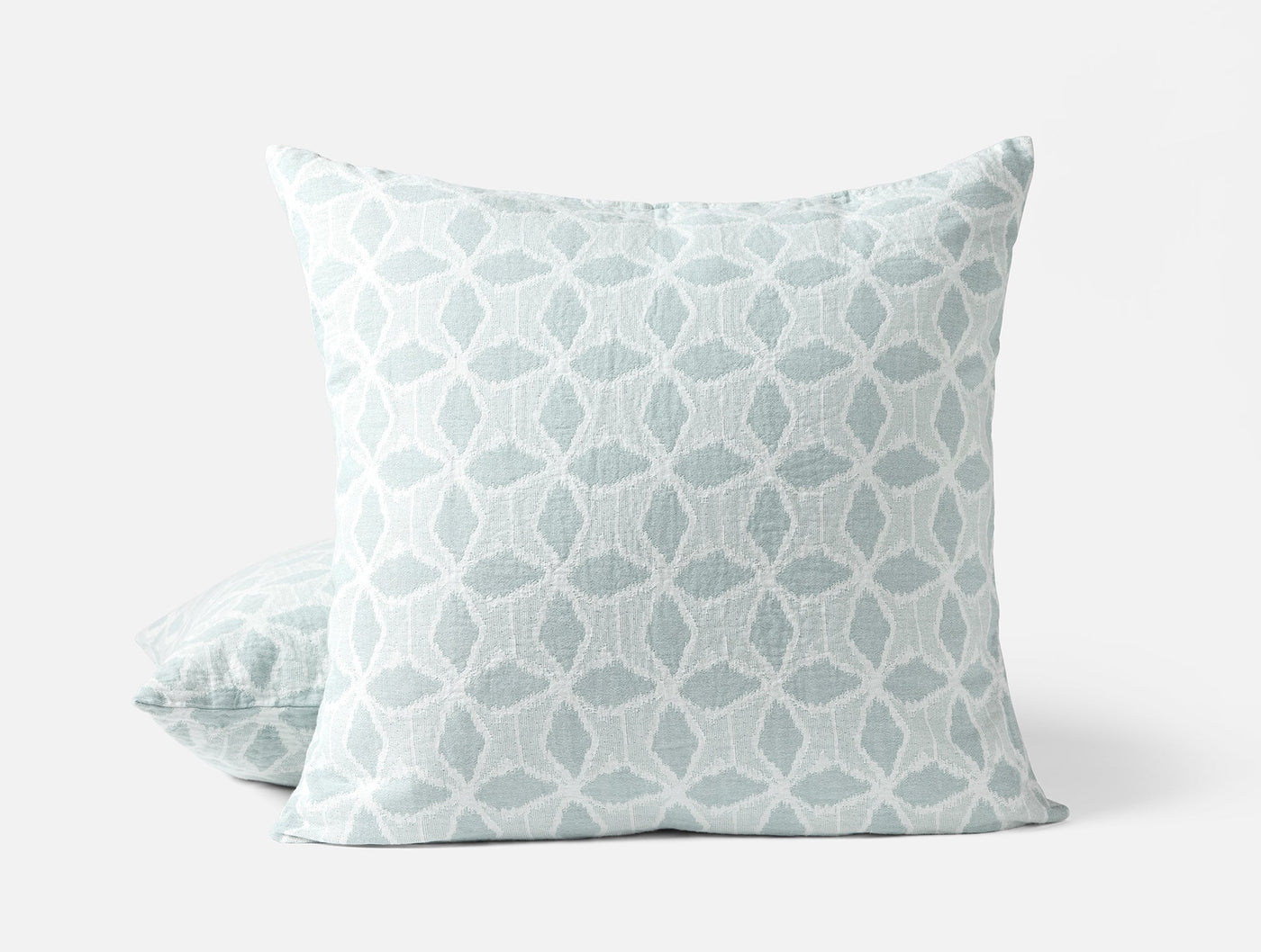 Close-up of Coyuchi Palomar sham in seafoam, geometric floral jacquard pattern, two shams stacked.