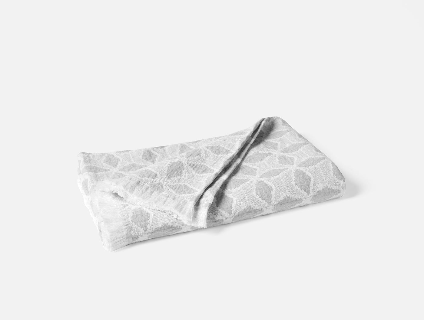 Folded Coyuchi Palomar throw in silver grey with geometric leaf jacquard pattern.