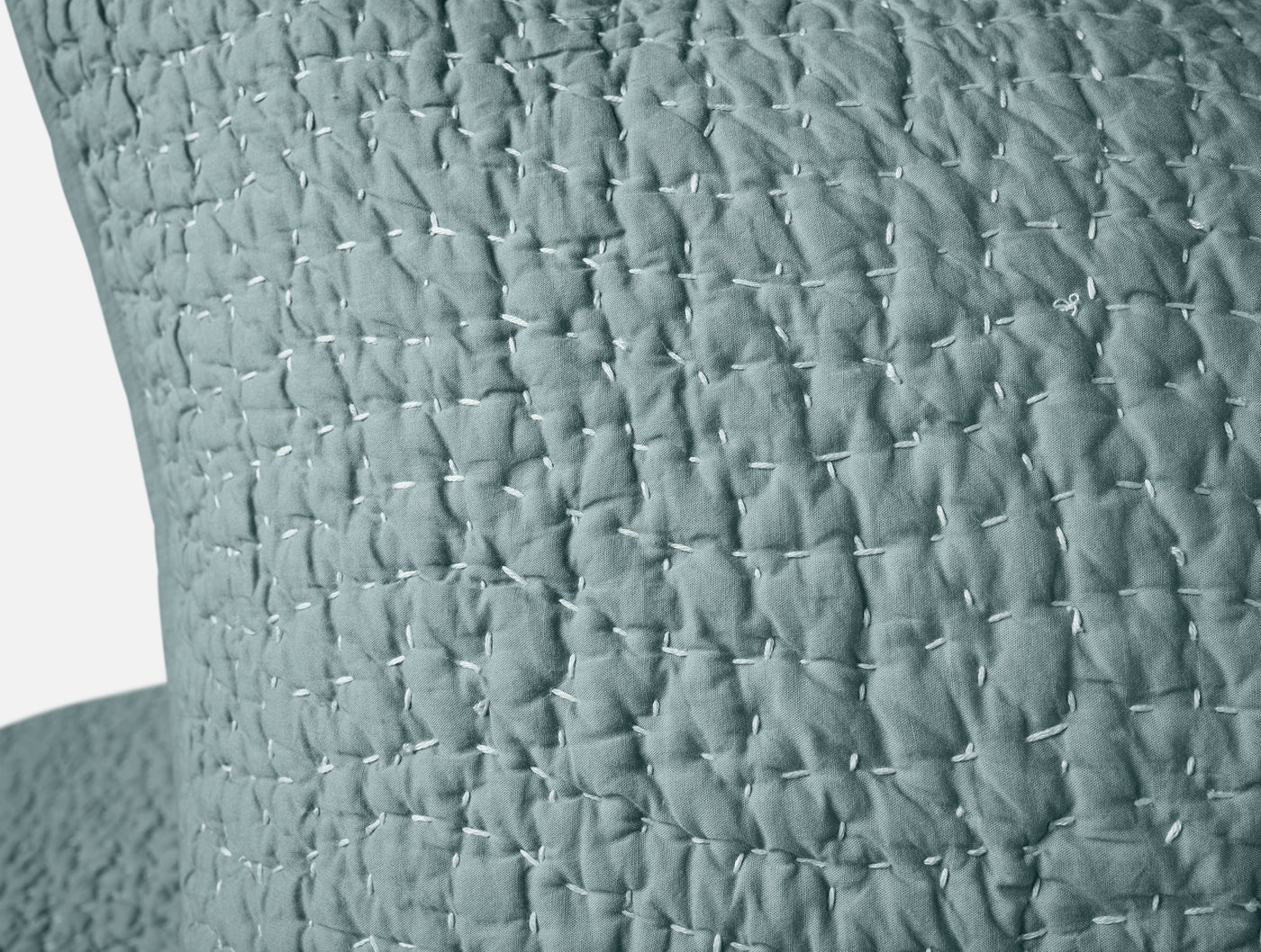 Close-up of slate blue quilted sham showing pebbled hand-stitched texture detail.