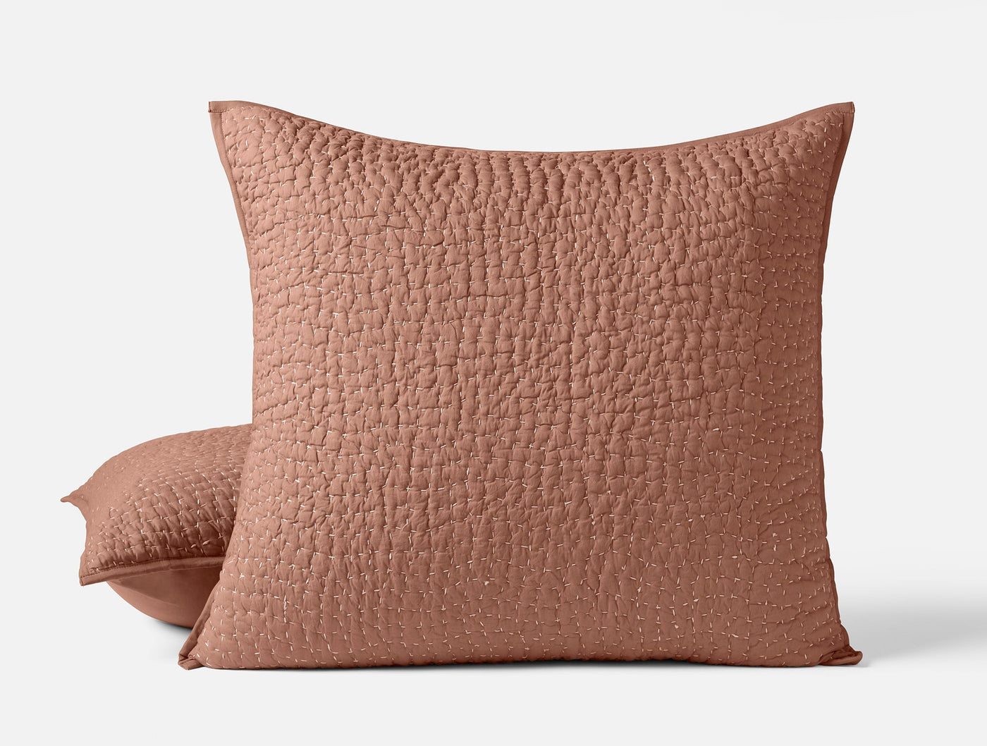 Close-up of two terracotta Coyuchi Pebbled Handstitched shams showing quilted texture detail.