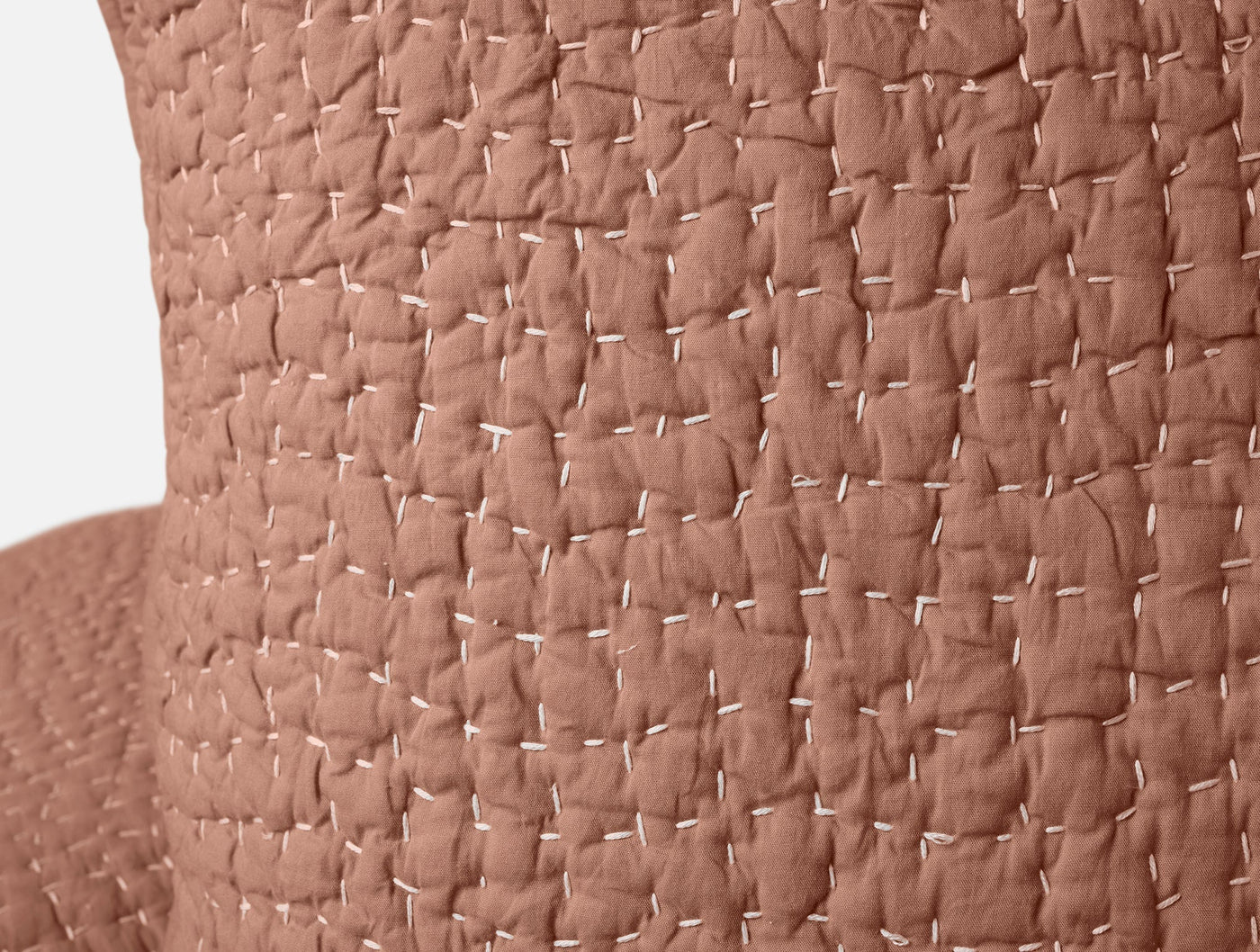 Close-up of terracotta Coyuchi Pebbled Handstitched sham showing textured waffle weave detail.