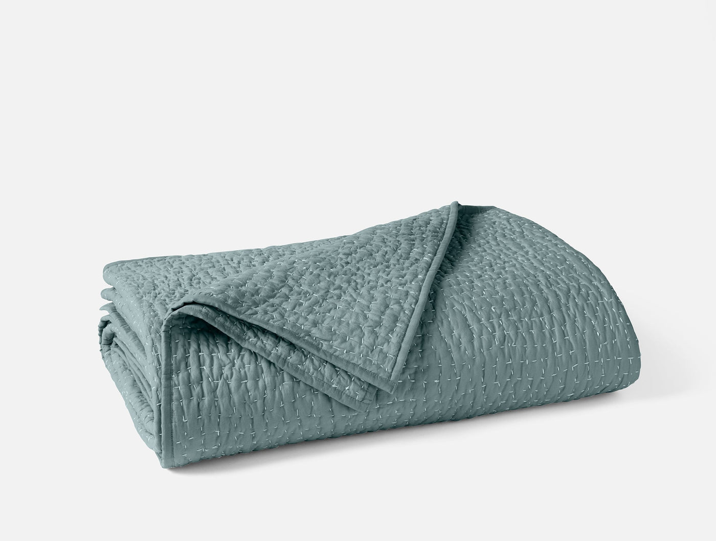 Coyuchi Pebbled Handstitched quilt folded, showing subtle pebble texture in seafoam.