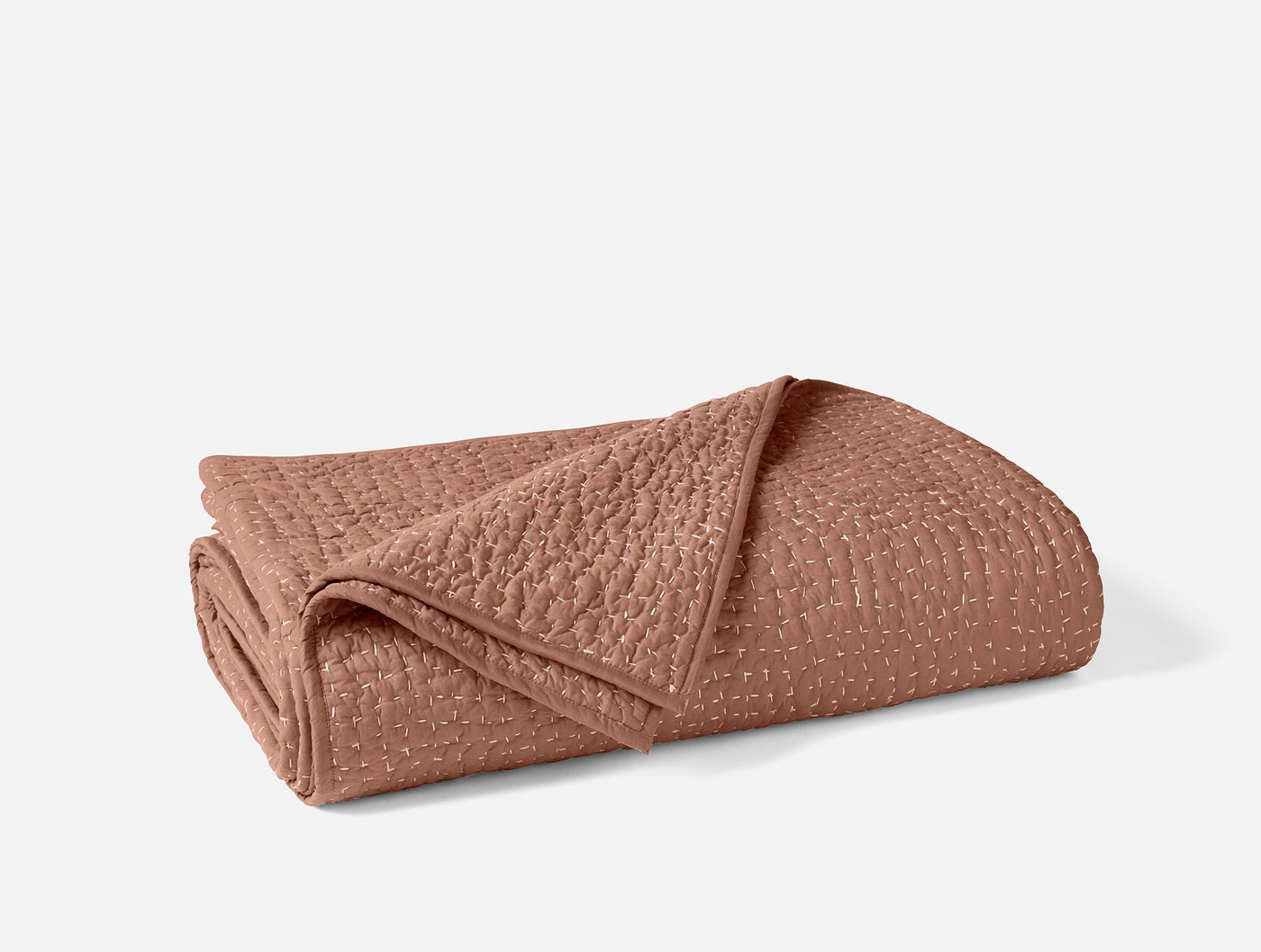 Coyuchi Pebbled Handstitched quilt folded, showing terracotta texture and handstitched detail.