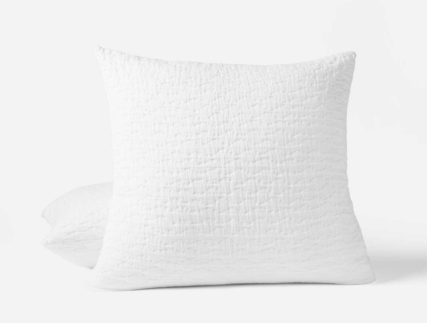 Coyuchi Pescadero Matelassé sham in white with textured woven surface, propped upright.