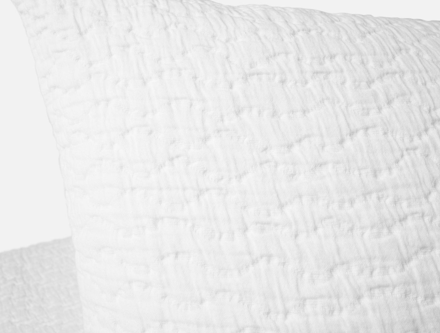 Close-up of white matelassé weave texture on Pescadero pillow sham corner.