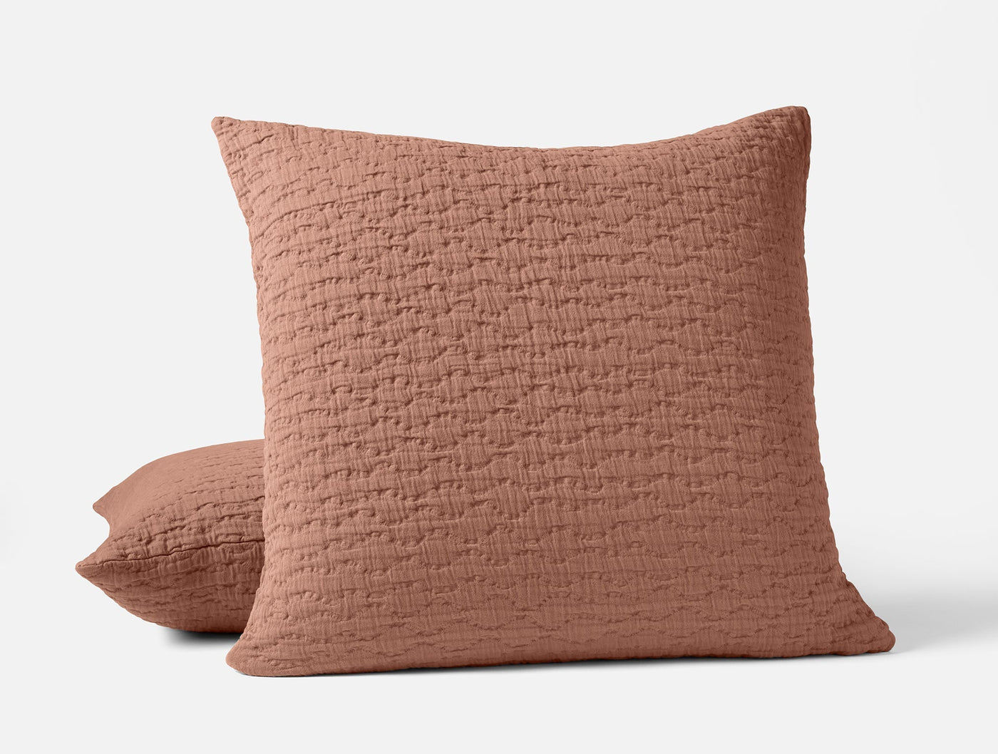 Terracotta matelassé pillow sham with quilted texture, shown front and side angled view.