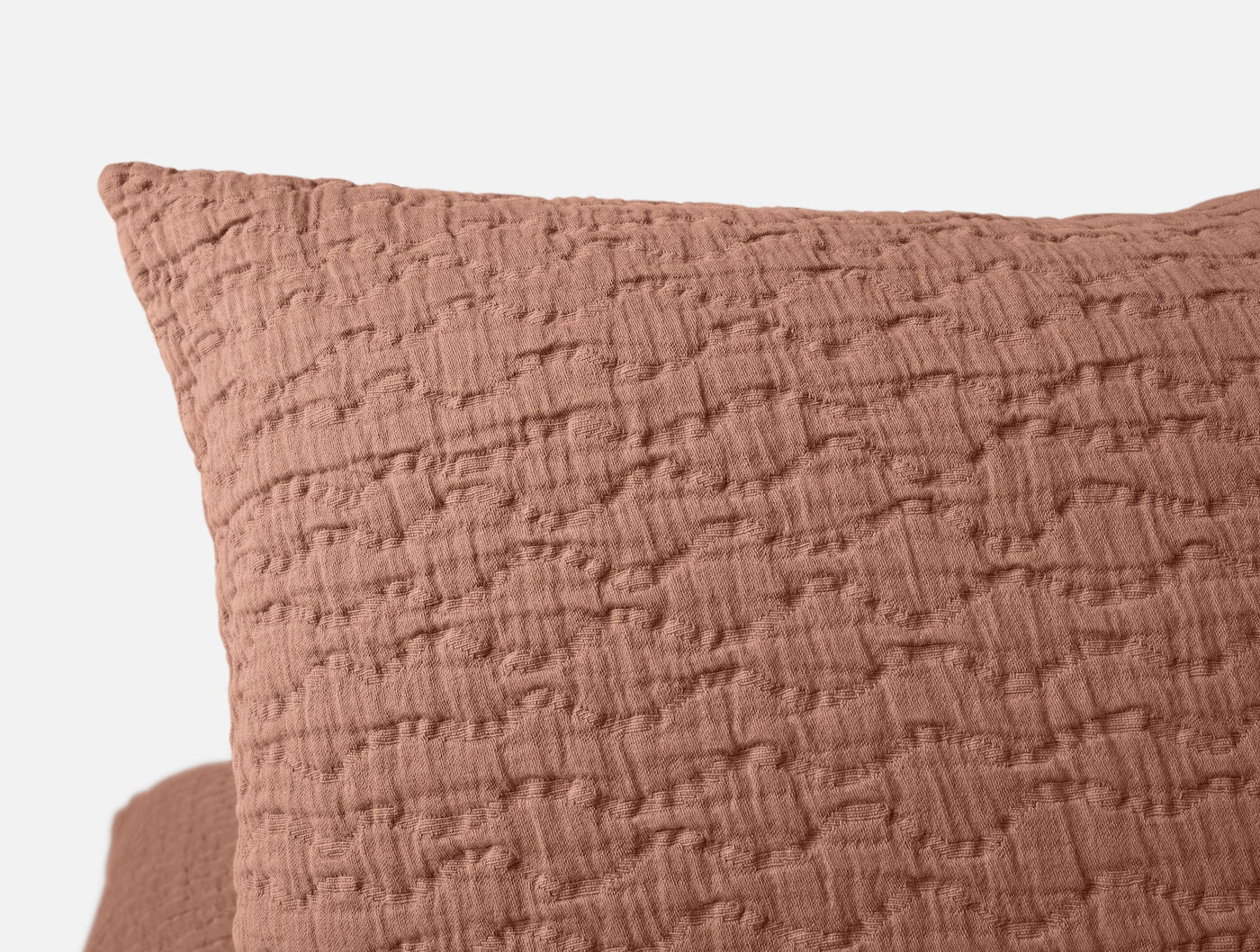 Close-up of terracotta matelassé weave texture on Pescadero pillow sham corner.