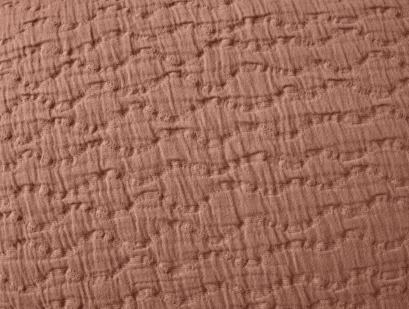Close-up of Coyuchi Pescadero Matelasse sham in terracotta, showing woven basket-weave texture.
