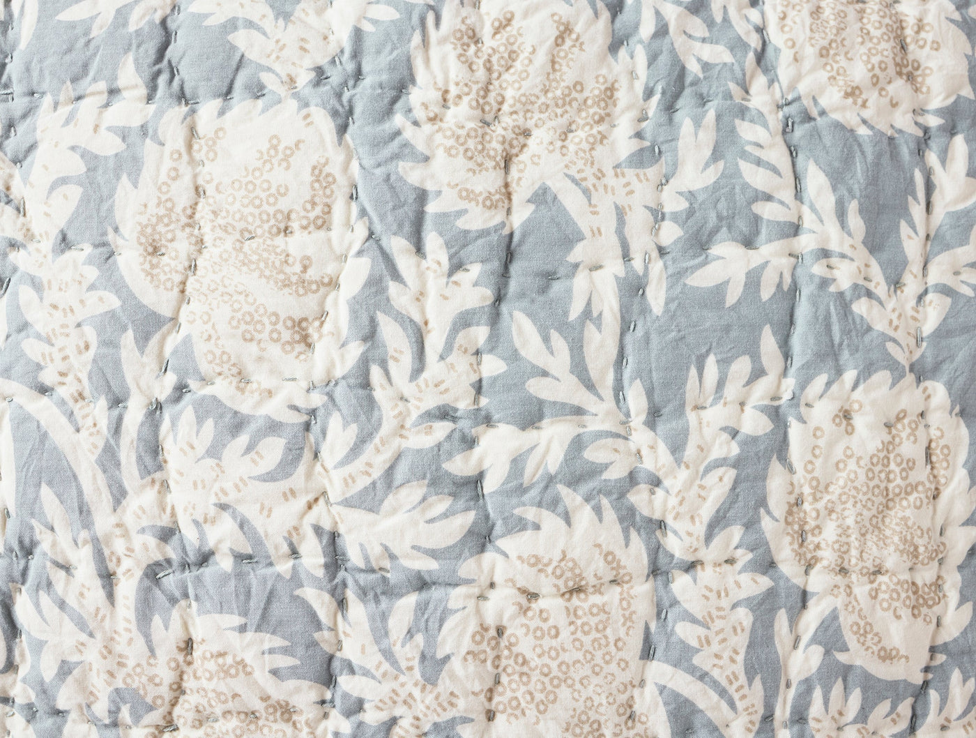 Close-up of Coyuchi Robles quilt showing slate blue floral block print and handstitched quilting detail.