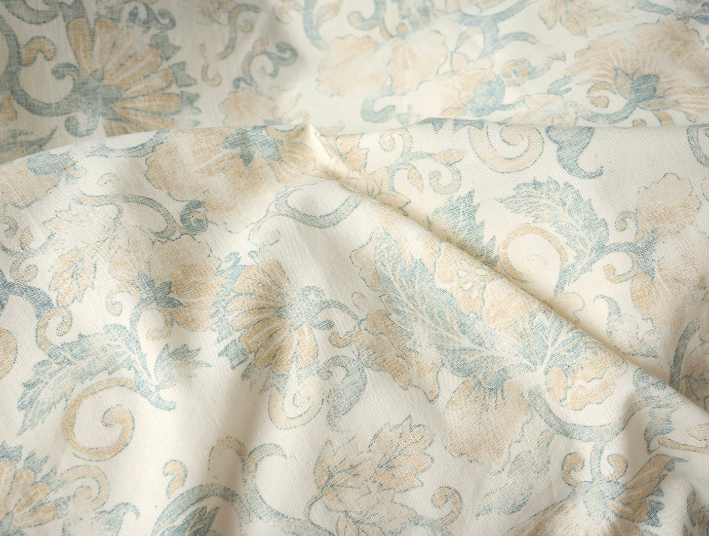 Close-up of Coyuchi Solana Print duvet cover showing ivory fabric with sage and sand floral pattern.