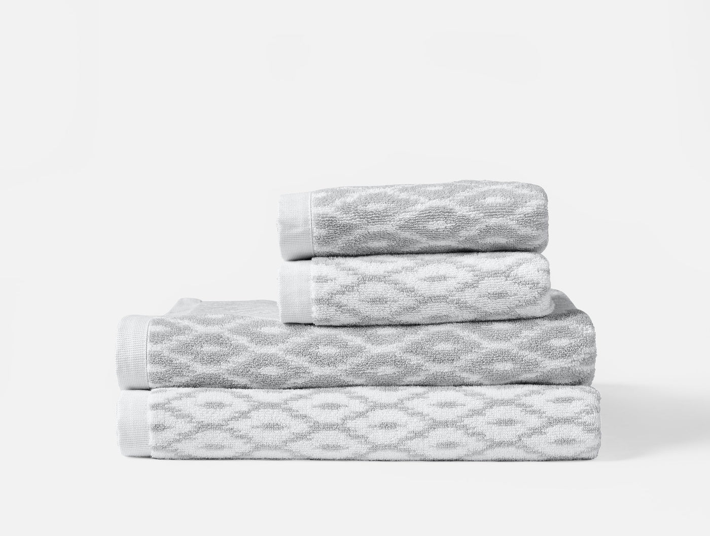 Stacked grey and white diamond-pattern Coyuchi Stinson towels, showing varied sizes.