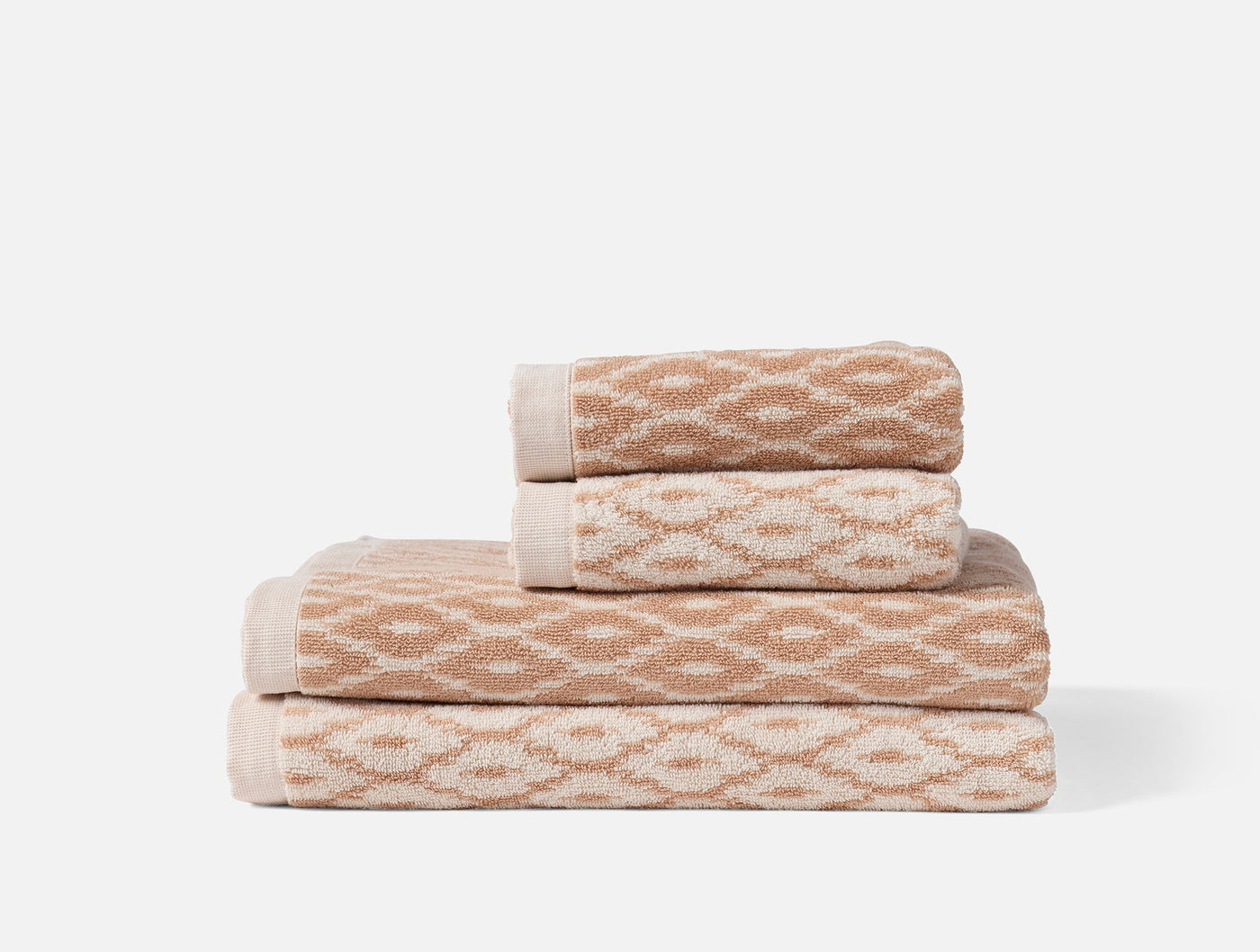 Close-up of stacked Coyuchi Stinson towels in sand with geometric diamond jacquard weave.