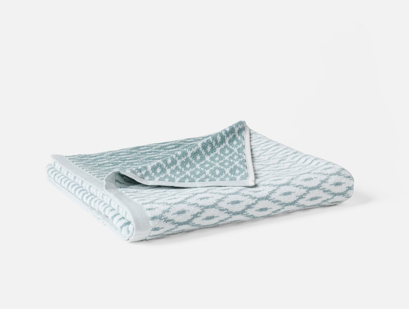 Close-up of folded Coyuchi Stinson bath towel in seafoam, diamond jacquard weave pattern visible.