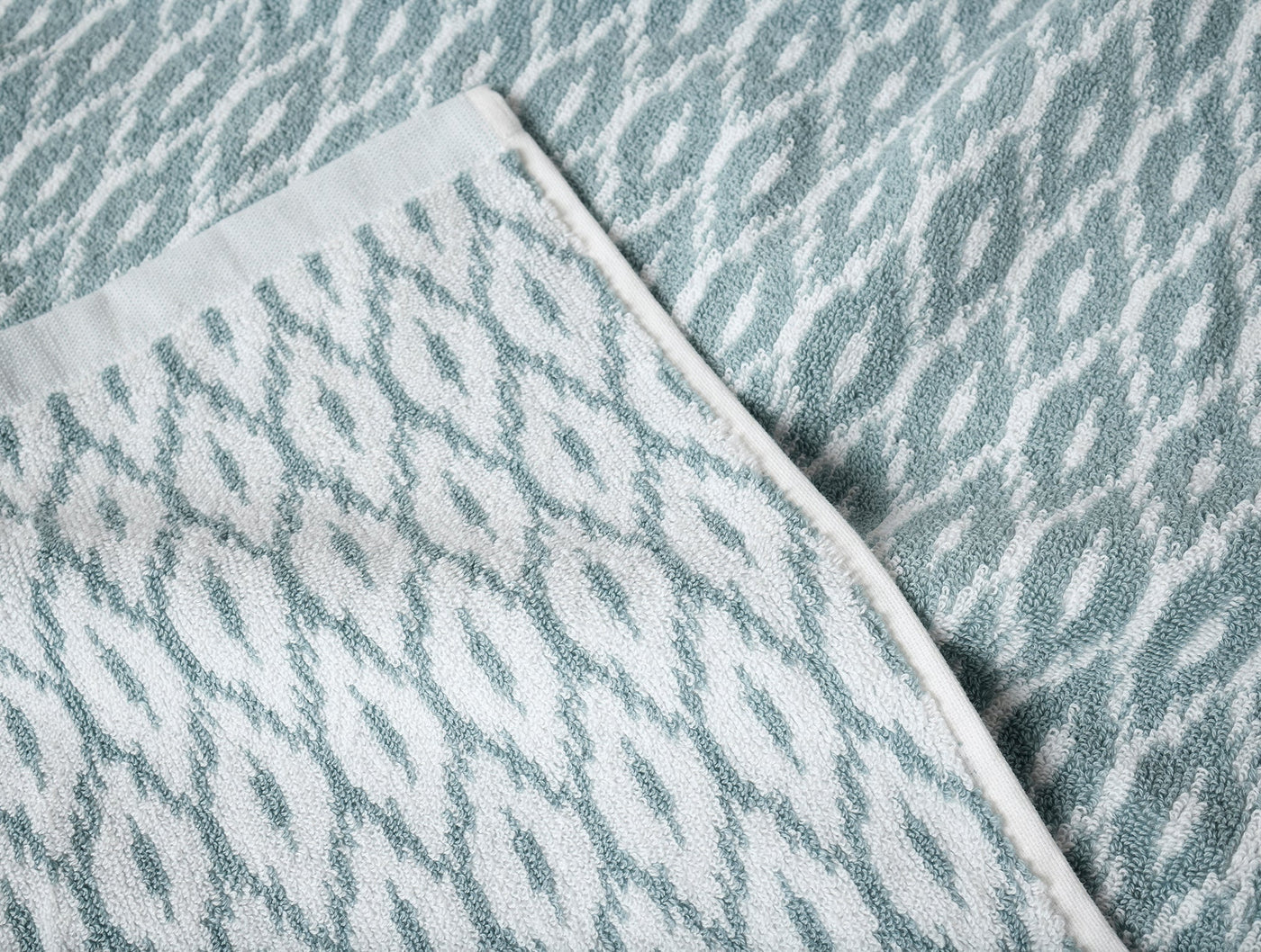 Close-up of Coyuchi Stinson towel in seafoam, showing diamond ikat jacquard weave texture.