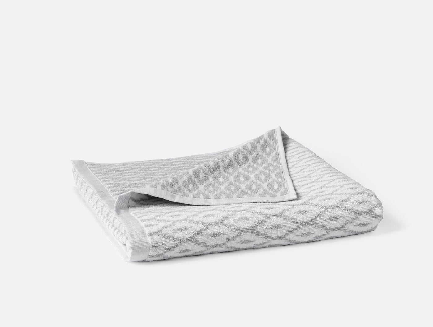 Folded grey bath towel showing diamond jacquard weave pattern and white hem detail.
