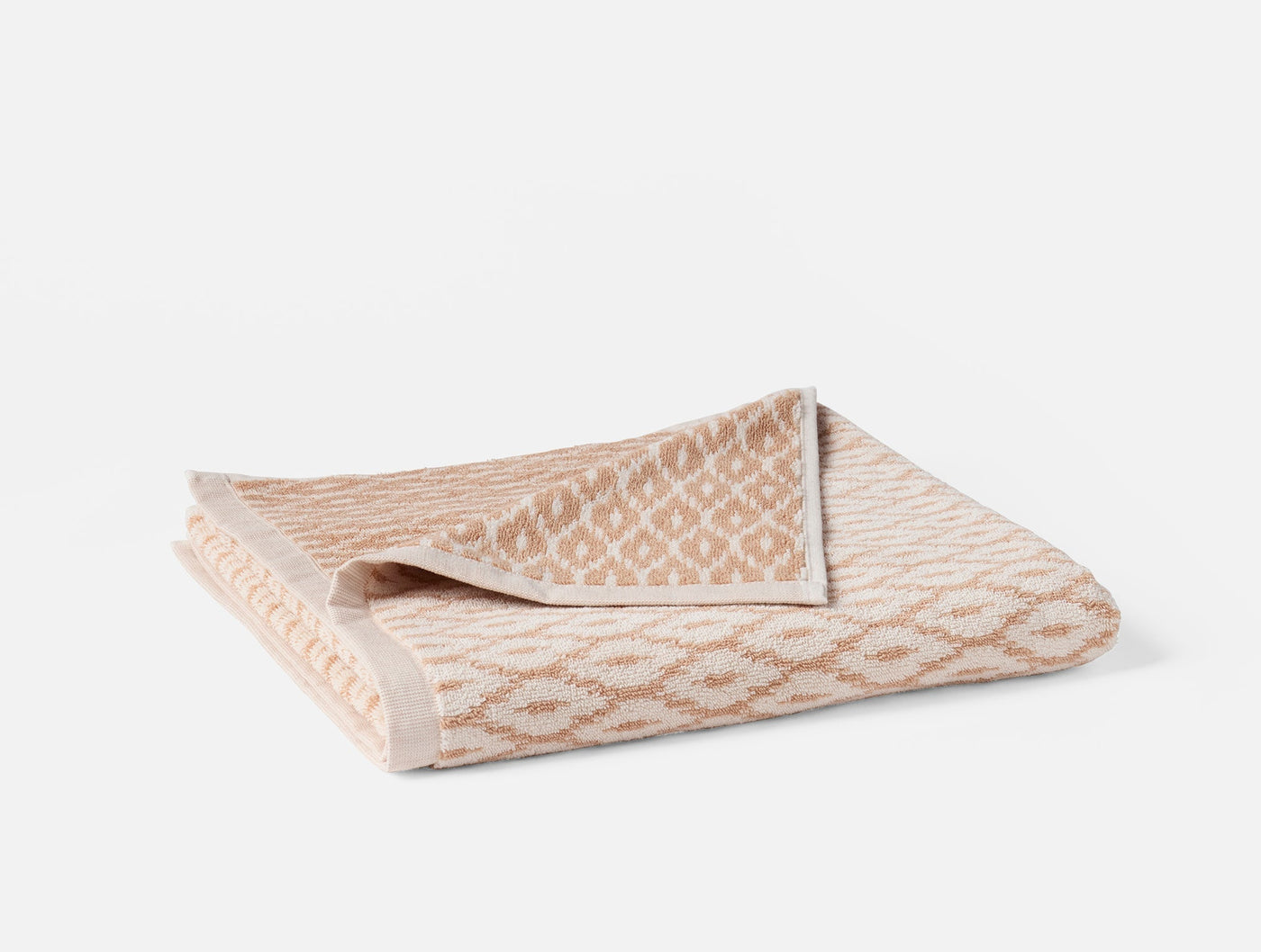 Folded hand towel showing blush and ivory diamond jacquard pattern with textured border.