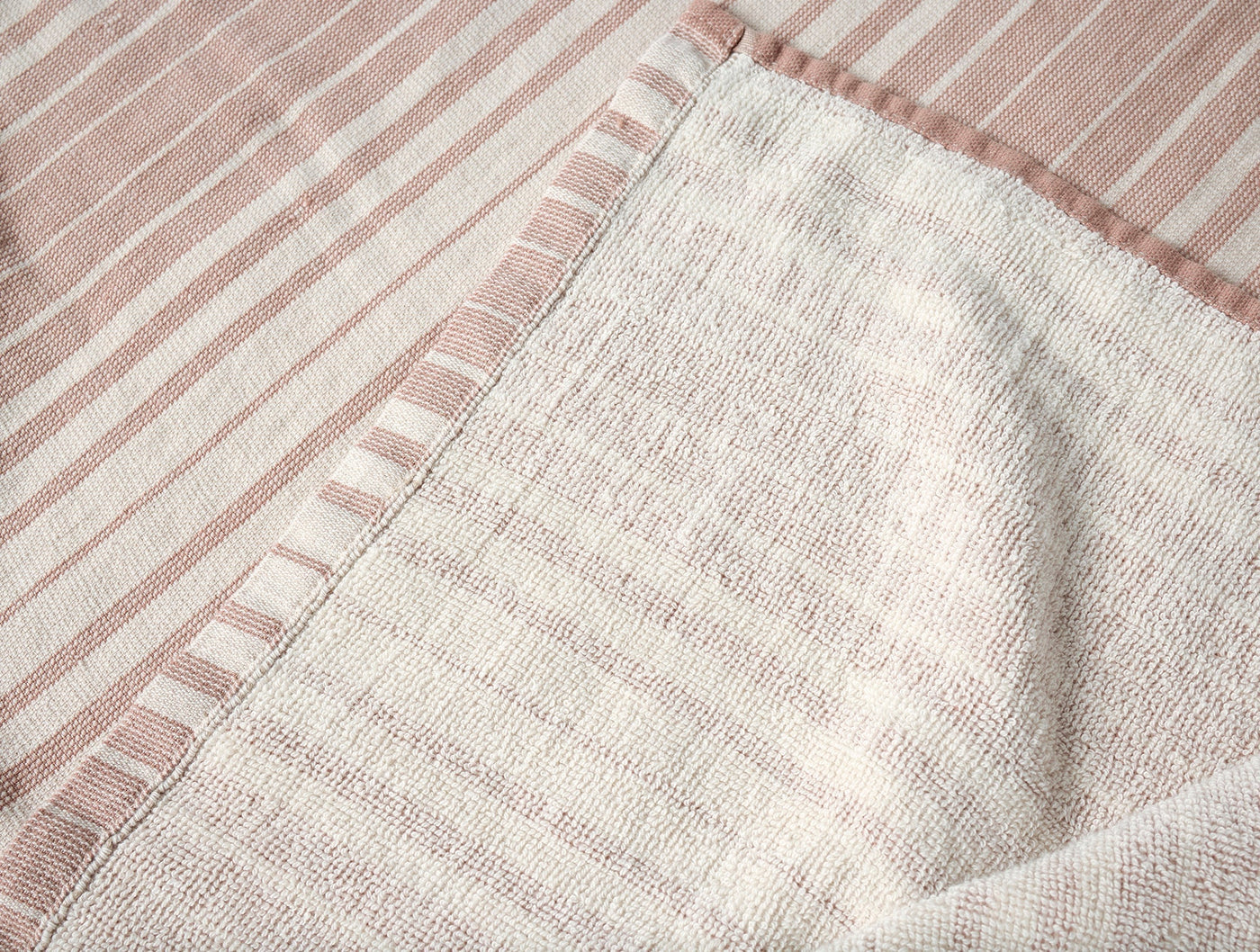 Close-up of Coyuchi Sycamore towel reverse, showing ivory waffle weave and blush stripe border detail.