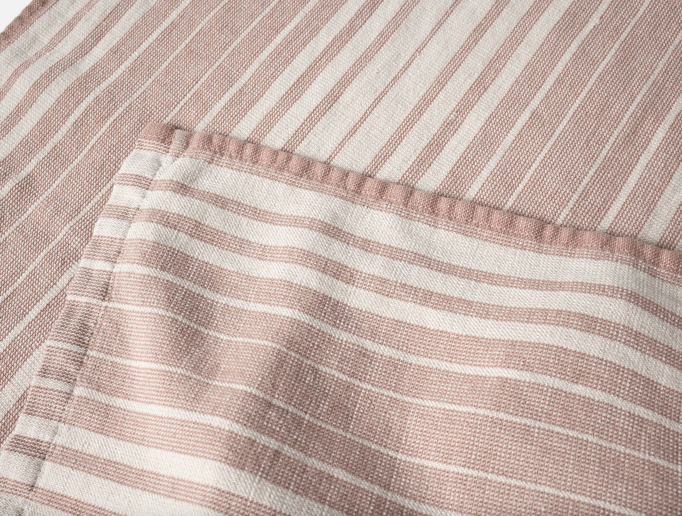 Close-up of Coyuchi Sycamore hand towel hem detail, rose and ivory woven stripes.