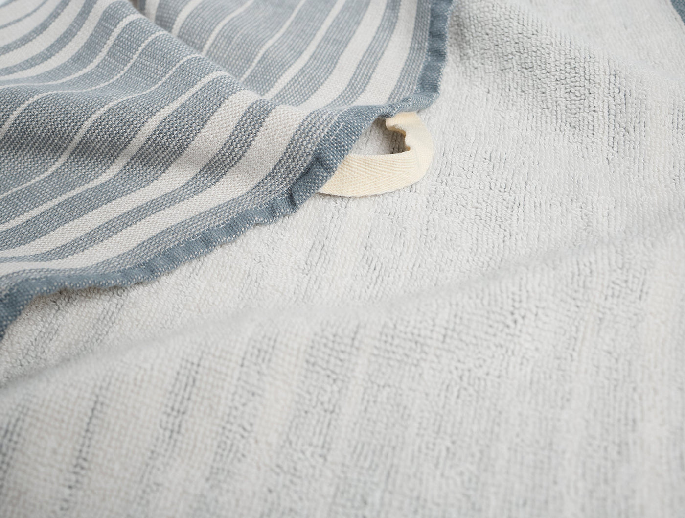 Close-up of Coyuchi Sycamore towel showing blue stripe border and ivory waffle-weave terry interior.
