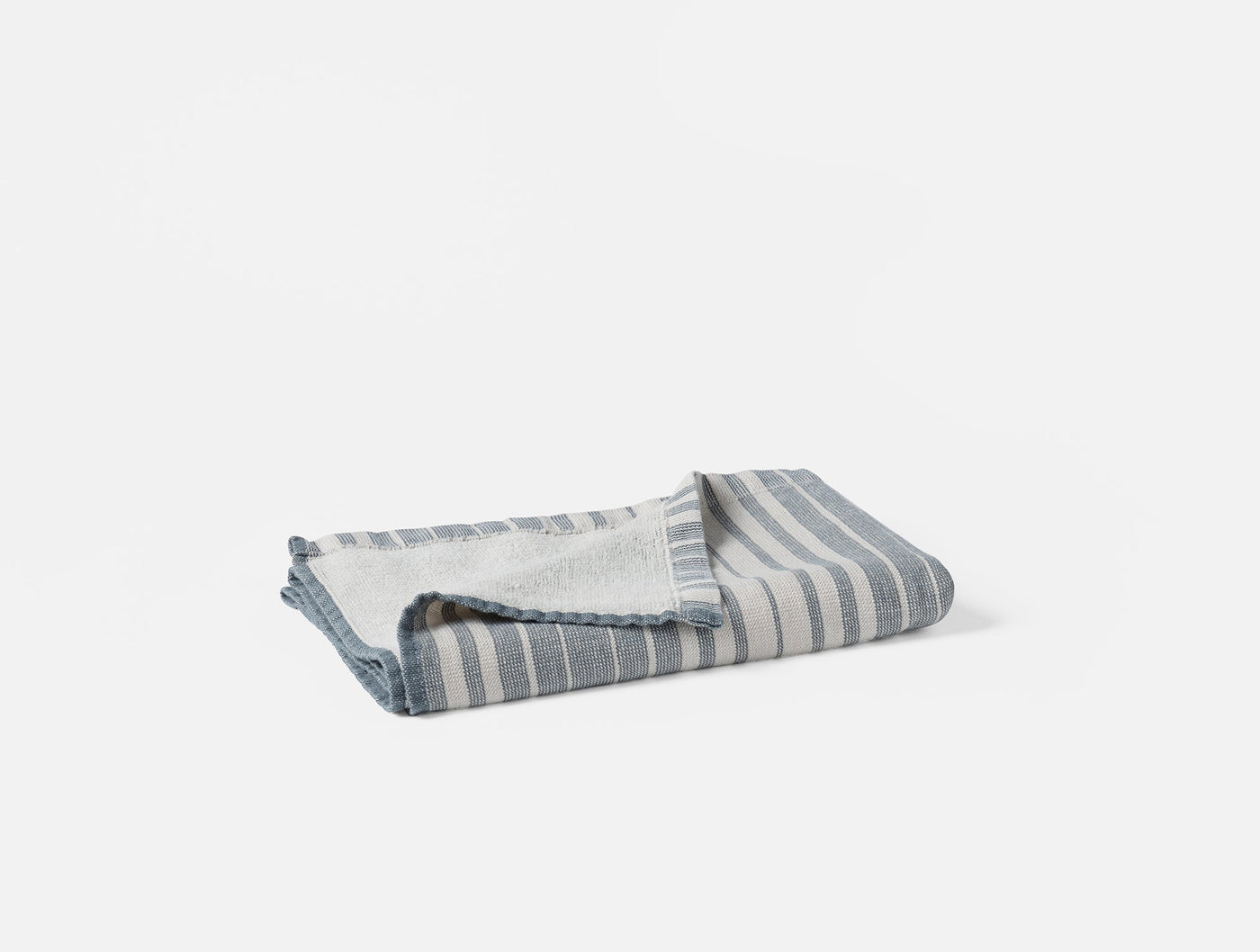 Folded Coyuchi Sycamore hand towel showing slate blue and white stripe pattern.