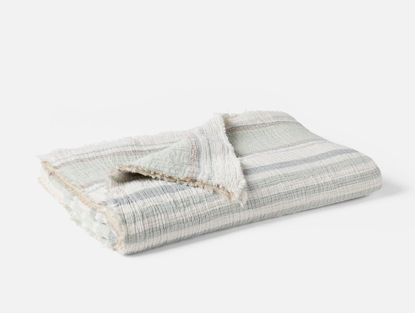 Folded Coyuchi Topanga Matelassé throw in ivory with soft grey stripes and fringe trim.