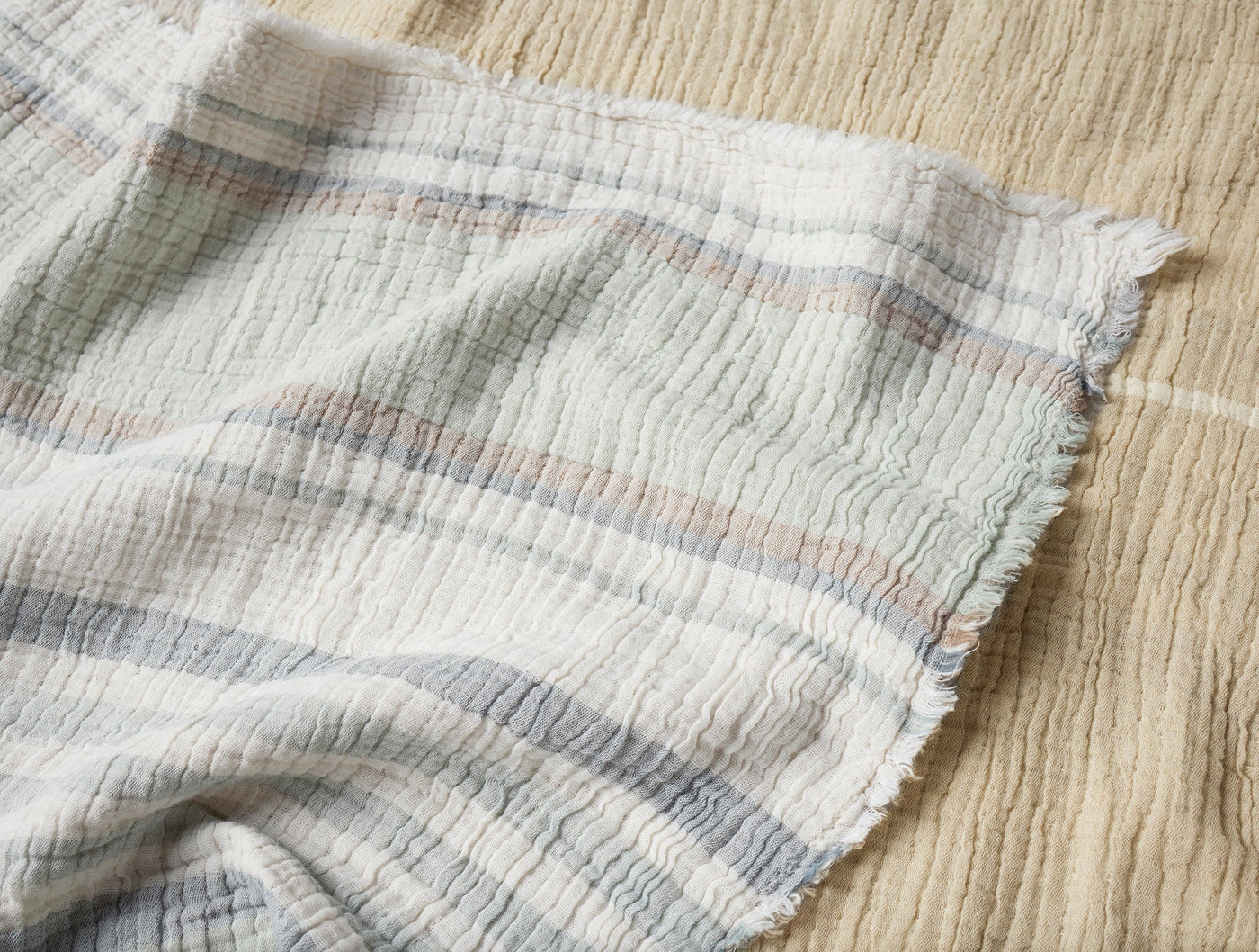 Close-up of Coyuchi Topanga Throw corner showing frayed hem and muted stripe texture.