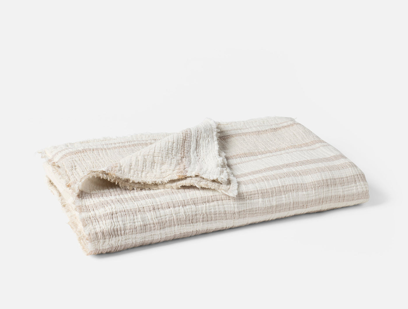 Folded ivory and taupe striped matelasse throw with fringe trim detail.