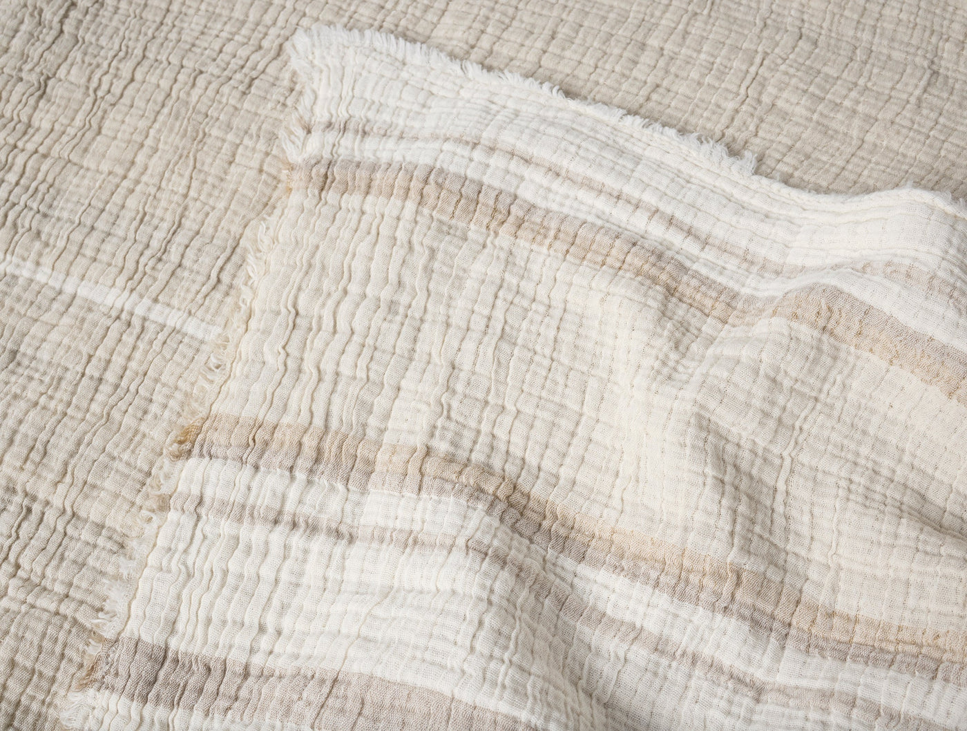 Close-up of Coyuchi Topanga Matelassé throw in ivory, showing crinkled cotton texture and fringe edge.