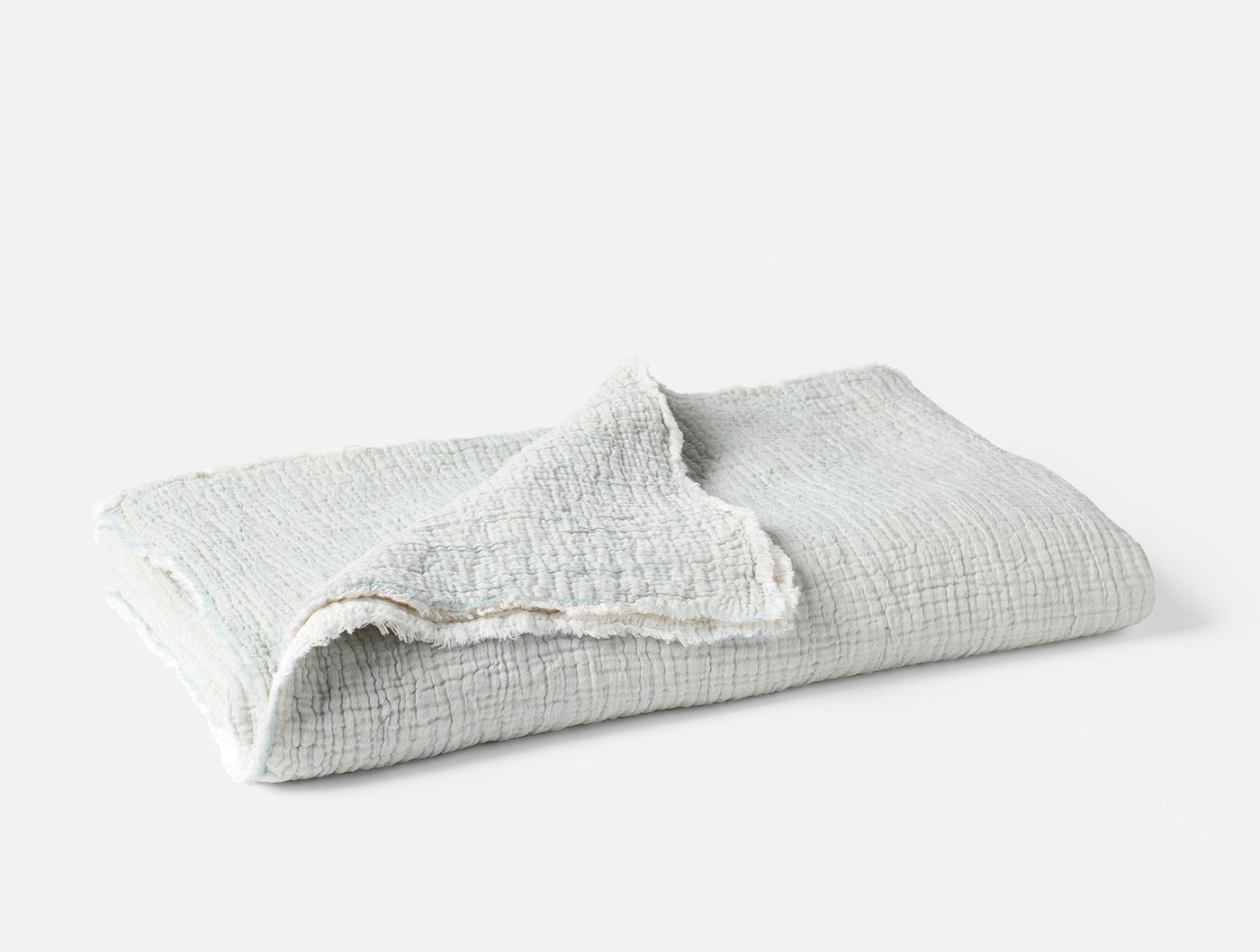 Folded Coyuchi Topanga Matelasse throw in mist, showing crinkled cotton texture.