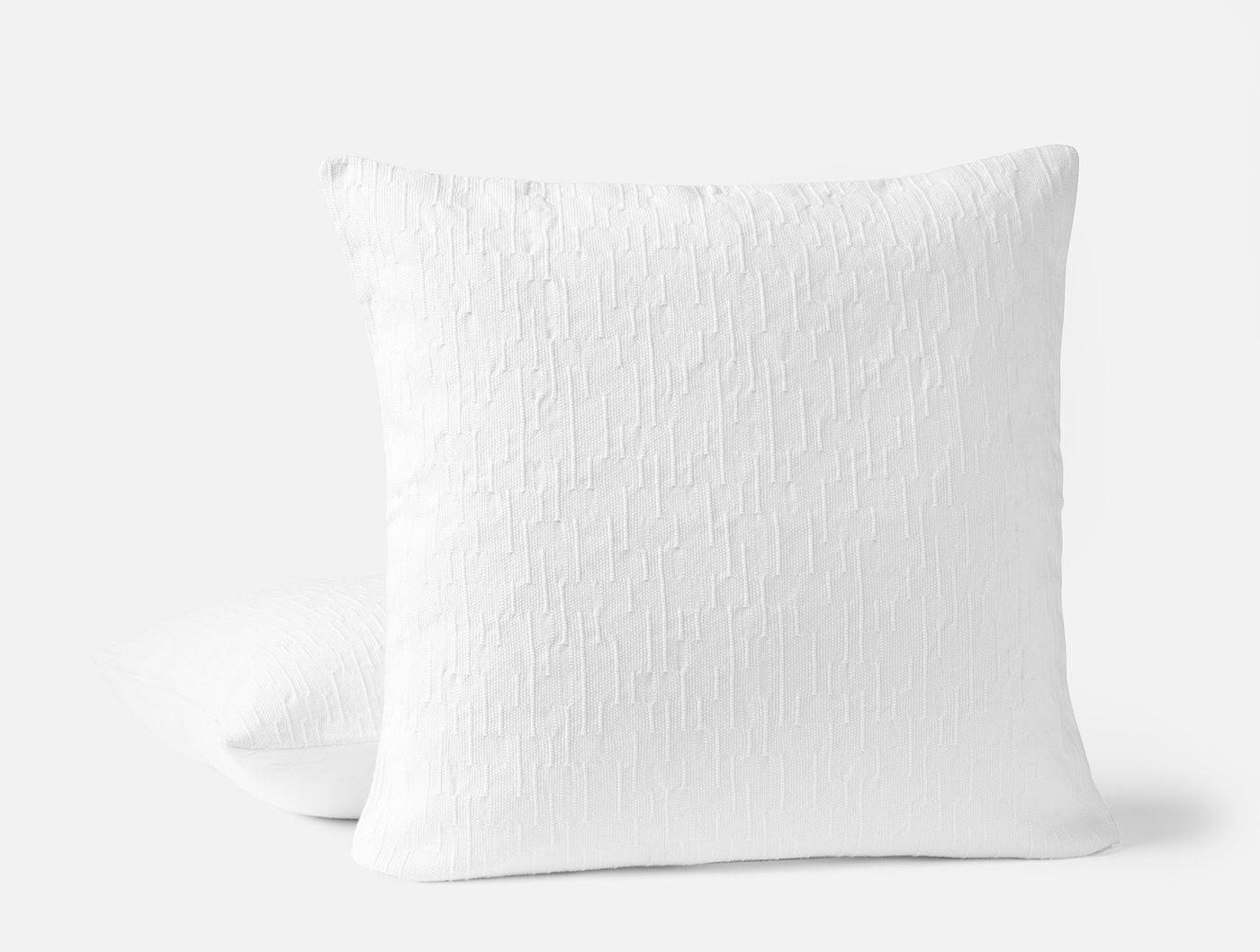 Close-up of Coyuchi Toro Canyon pillow in white with textured woven surface, two pillows stacked.